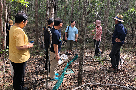 Visitors and researchers standing in bushland beside ecological field equipment